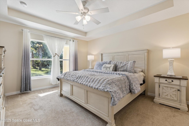 carpeted bedroom with a tray ceiling and ceiling fan