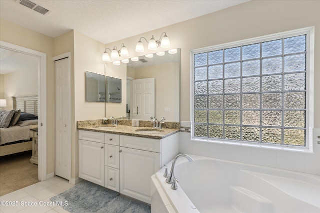 bathroom featuring a textured ceiling, a relaxing tiled tub, tile patterned floors, and a healthy amount of sunlight