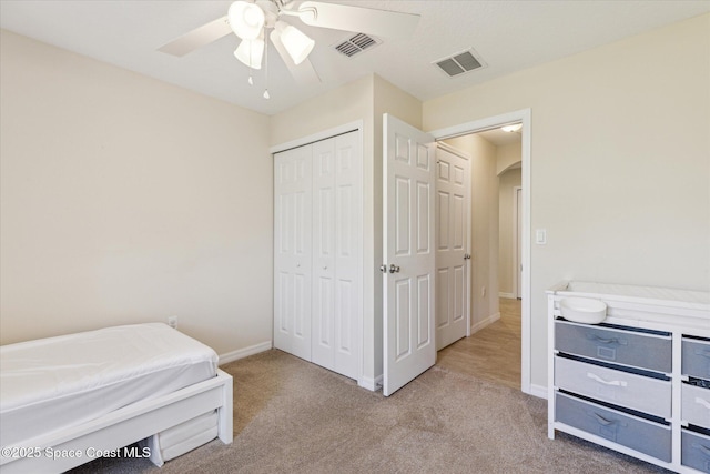 bedroom with ceiling fan, light carpet, and a closet