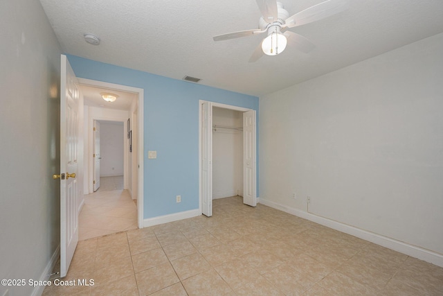 unfurnished bedroom featuring ceiling fan, a closet, light tile patterned floors, and a textured ceiling