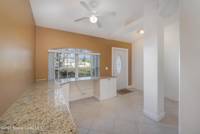 kitchen with light stone countertops, ceiling fan, white cabinets, vaulted ceiling, and light tile patterned floors