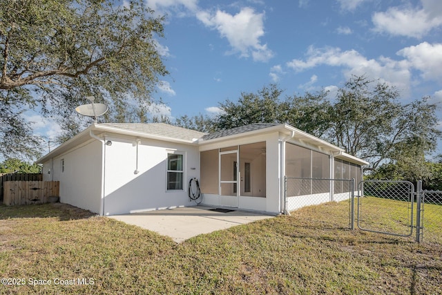 rear view of property featuring a lawn, a patio area, and a sunroom