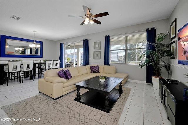 living room with ceiling fan with notable chandelier