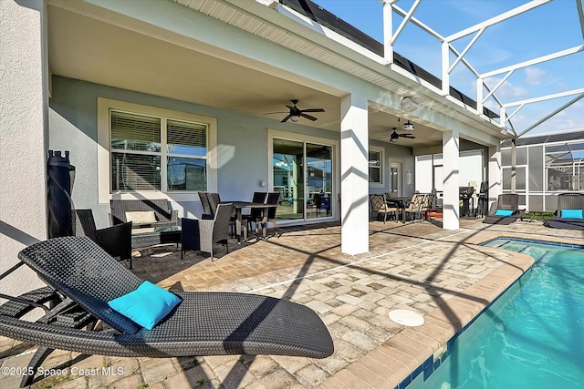 view of swimming pool featuring a patio area, ceiling fan, and glass enclosure