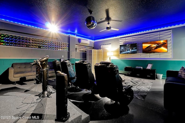 home theater room featuring a textured ceiling, a wall mounted AC, and ceiling fan