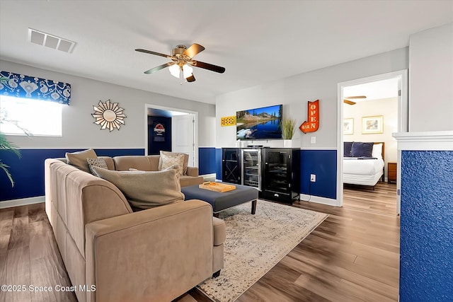 living room featuring bar area, ceiling fan, and hardwood / wood-style flooring