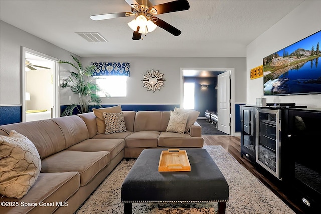 living room with ceiling fan, wood-type flooring, and a textured ceiling