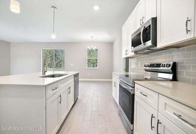 kitchen featuring white cabinets, appliances with stainless steel finishes, a kitchen island with sink, and sink