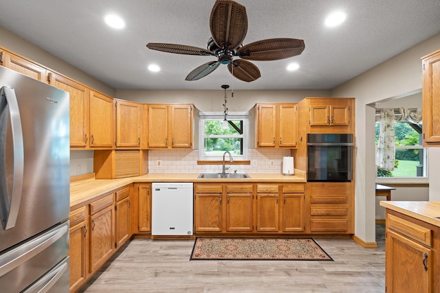 kitchen with ceiling fan, sink, stainless steel fridge, white dishwasher, and oven