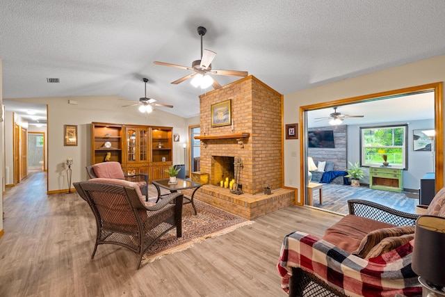 living room with a fireplace, a textured ceiling, light wood-type flooring, and lofted ceiling