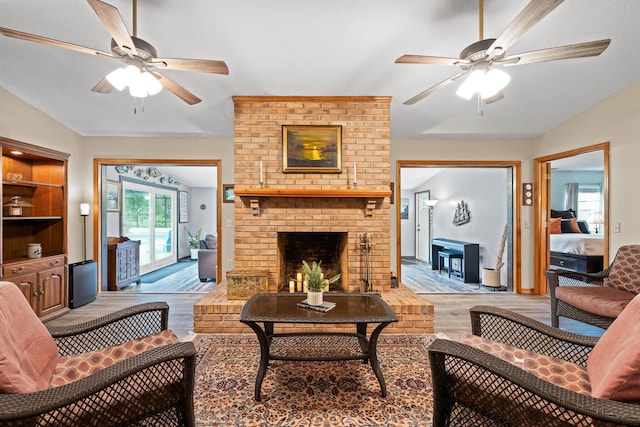 living room with ceiling fan, light hardwood / wood-style flooring, a fireplace, and vaulted ceiling