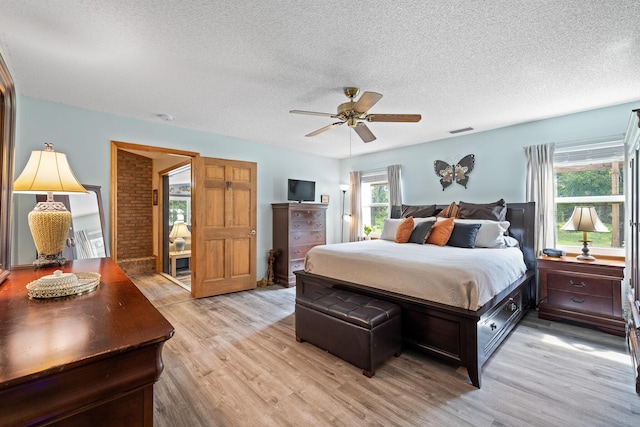 bedroom featuring ceiling fan, light wood-type flooring, and a textured ceiling