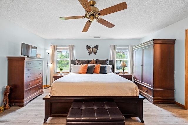 bedroom with multiple windows, a textured ceiling, light hardwood / wood-style flooring, and ceiling fan