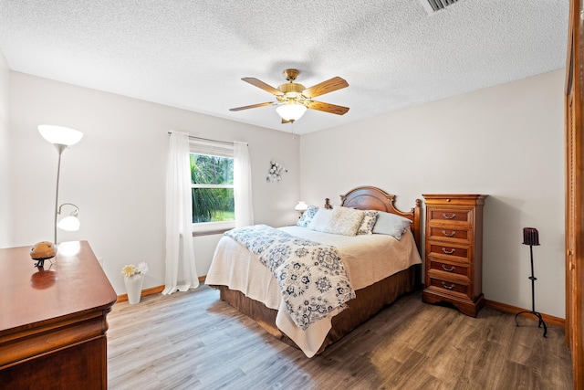 bedroom featuring ceiling fan, hardwood / wood-style floors, and a textured ceiling