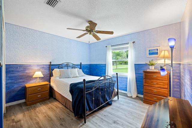 bedroom with ceiling fan, light hardwood / wood-style flooring, and a textured ceiling