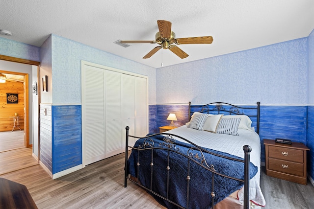 bedroom featuring wood-type flooring, a textured ceiling, a closet, and ceiling fan