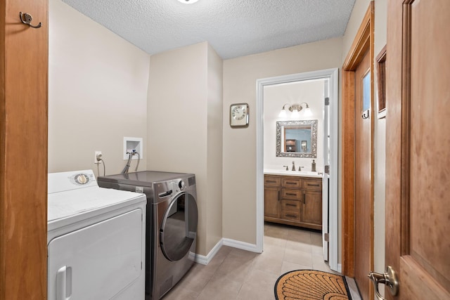 laundry room featuring washer and dryer, light tile patterned floors, and a textured ceiling