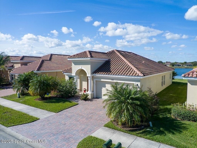 mediterranean / spanish-style house featuring a garage, a water view, and a front yard