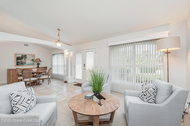 living room featuring french doors, light tile patterned flooring, and lofted ceiling