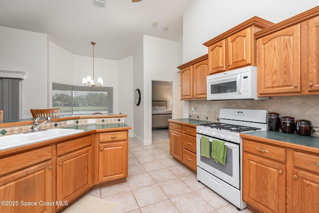 kitchen featuring backsplash, sink, white appliances, and a notable chandelier