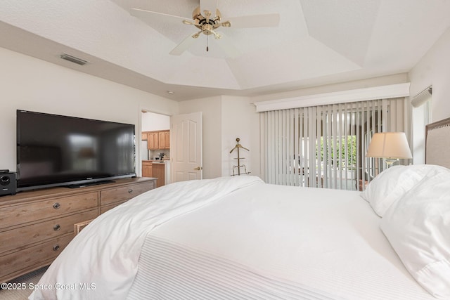 bedroom with access to exterior, ceiling fan, and a raised ceiling