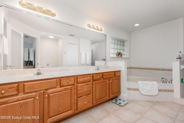 bathroom with tile patterned floors, vanity, and tiled tub