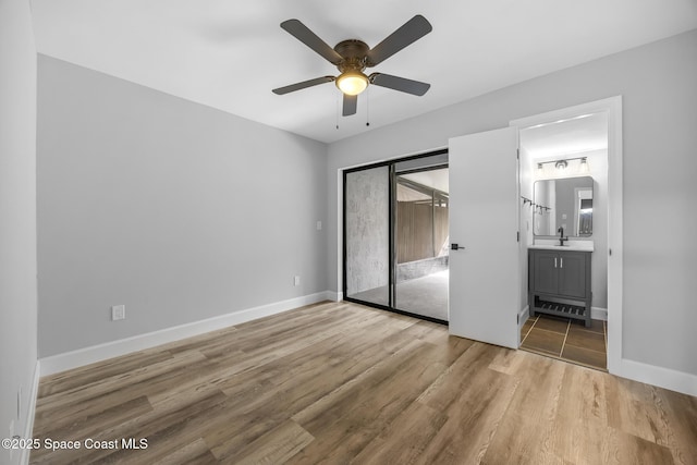 unfurnished bedroom with ceiling fan, sink, hardwood / wood-style flooring, connected bathroom, and a closet