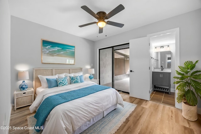 bedroom featuring ceiling fan, sink, ensuite bathroom, and light wood-type flooring