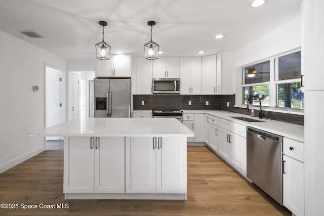 kitchen with white cabinets, appliances with stainless steel finishes, a center island, and sink