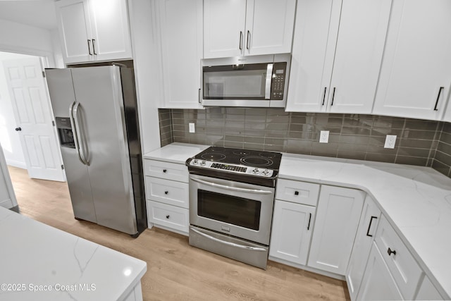 kitchen with light stone countertops, white cabinets, stainless steel appliances, and light hardwood / wood-style floors