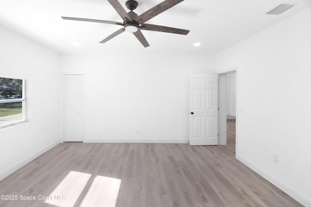 empty room with ceiling fan and light hardwood / wood-style floors