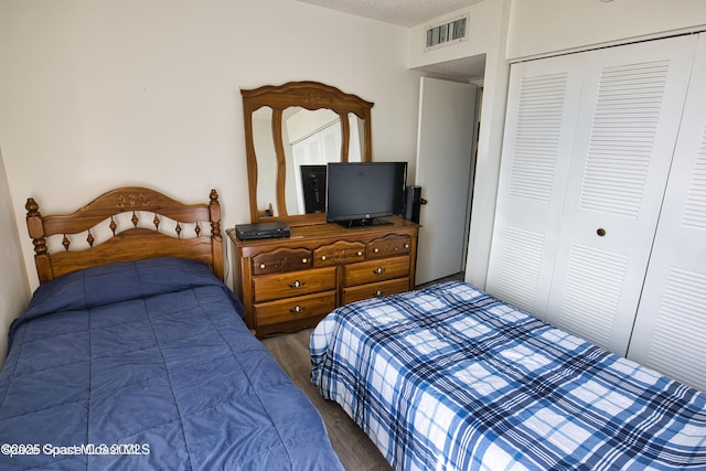 bedroom featuring a textured ceiling, dark hardwood / wood-style flooring, and a closet