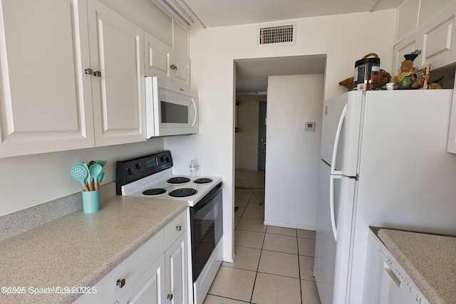 kitchen with light tile patterned floors, white cabinets, and white appliances