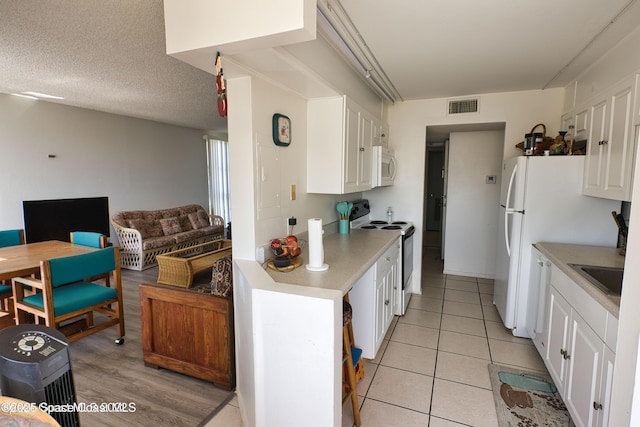 4700 Ocean Beach Blvd Unit 404, Cocoa Beach, FL 32931 - kitchen with electric stove, light countertops, white cabinets, open floor plan, and white microwave