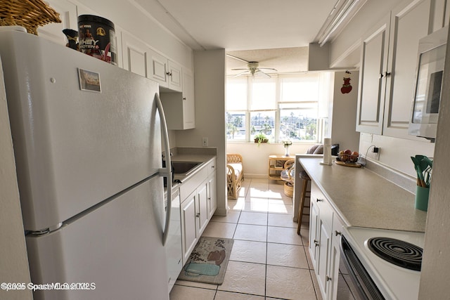 4700 Ocean Beach Blvd Unit 404, Cocoa Beach, FL 32931 - kitchen featuring white appliances, ceiling fan, light tile patterned floors, and white cabinetry