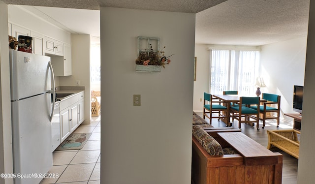 4700 Ocean Beach Blvd Unit 404, Cocoa Beach, FL 32931 - kitchen with white appliances, white cabinets, light countertops, a textured ceiling, and light tile patterned floors