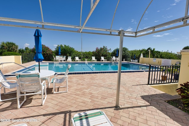 view of pool with glass enclosure and a patio