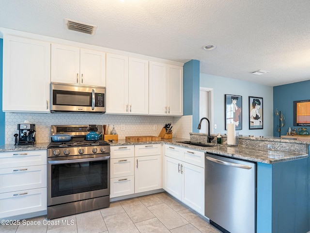 kitchen featuring white cabinets, appliances with stainless steel finishes, kitchen peninsula, and sink