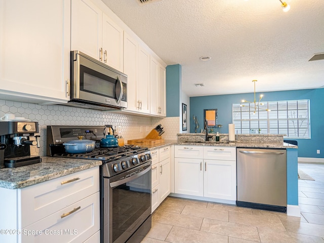 kitchen with white cabinets, sink, appliances with stainless steel finishes, kitchen peninsula, and a chandelier