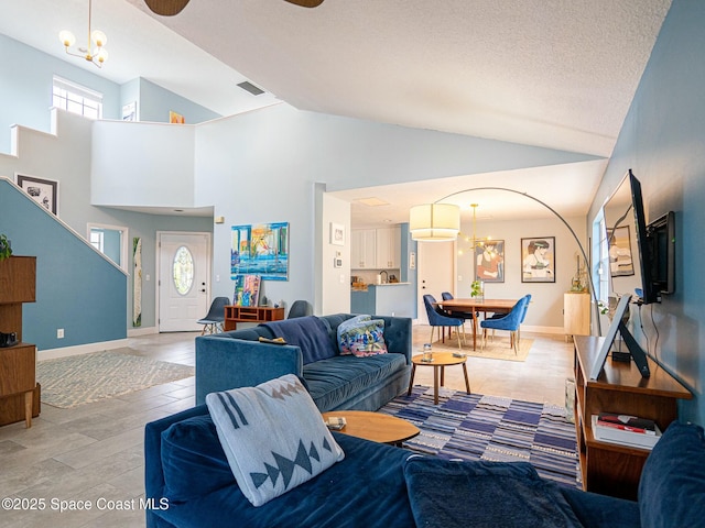 living room with ceiling fan with notable chandelier, a textured ceiling, and high vaulted ceiling