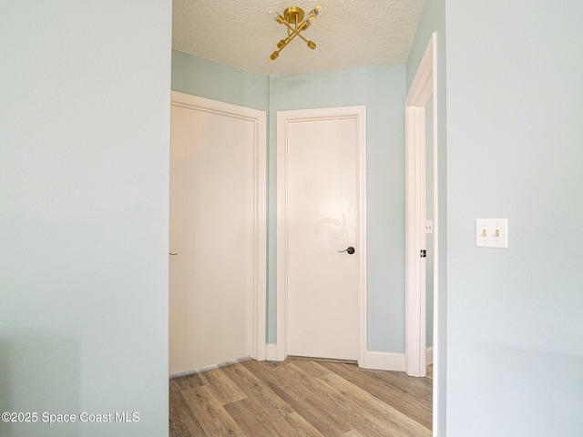 hallway with light wood-type flooring and a textured ceiling