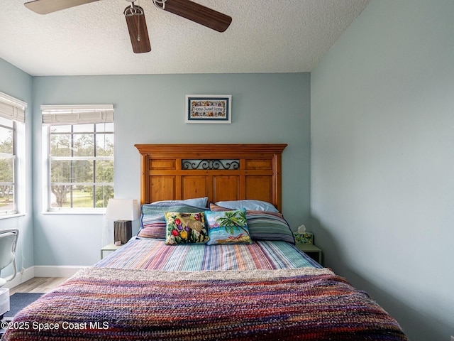 bedroom with a textured ceiling, light hardwood / wood-style flooring, and ceiling fan