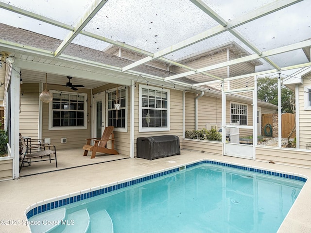 view of pool featuring glass enclosure, ceiling fan, and a patio area