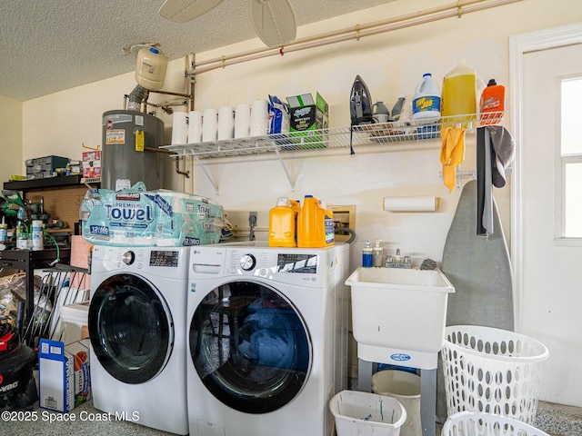 clothes washing area featuring sink, washing machine and dryer, a textured ceiling, and gas water heater