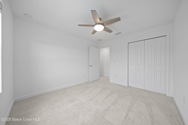 unfurnished bedroom with ceiling fan, light colored carpet, and a closet