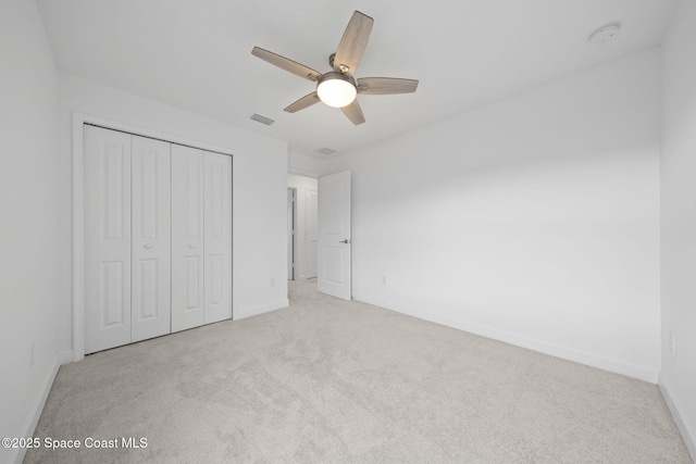 unfurnished bedroom with ceiling fan, light colored carpet, and a closet