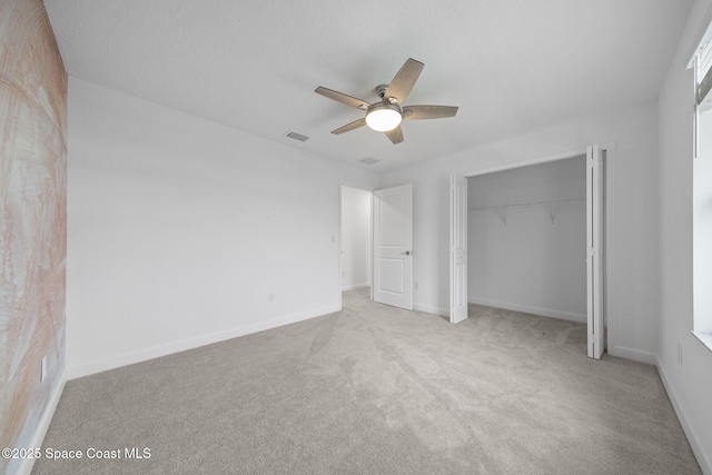 unfurnished bedroom featuring ceiling fan, light colored carpet, and a closet