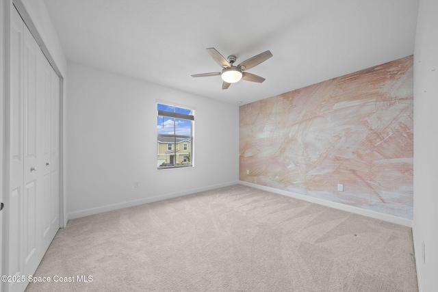 unfurnished bedroom featuring ceiling fan, light colored carpet, and a closet