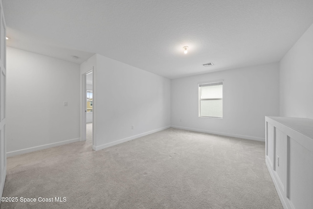 spare room with light carpet and a textured ceiling