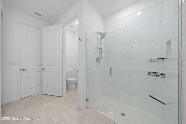 bathroom featuring toilet, hardwood / wood-style floors, and an enclosed shower